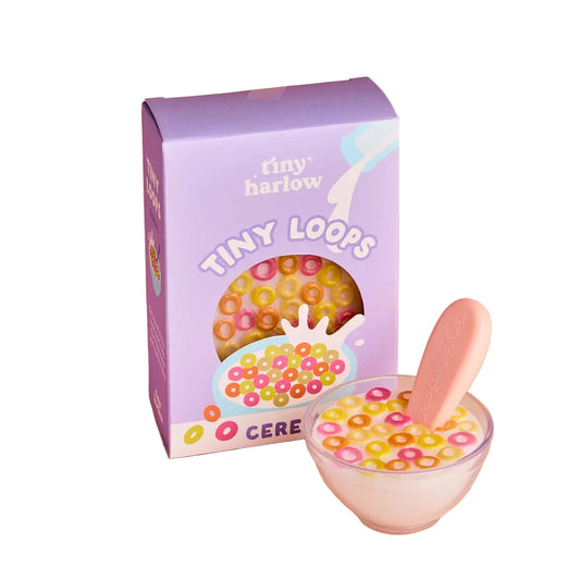 Box of 'tiny harlow' Tiny Loops cereal with a bowl of cereal and pink spoon on a beige background