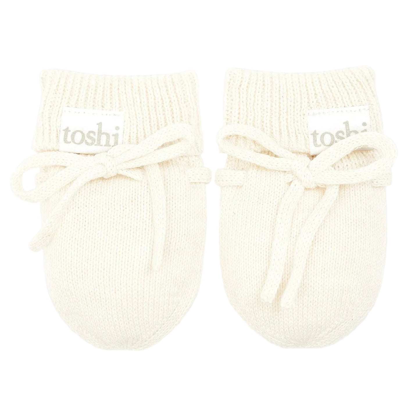 Pair of cream-colored baby booties with 'toshi' branding on a light gray background