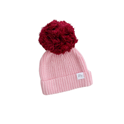 Pink beanie with a red pom-pom on a white background