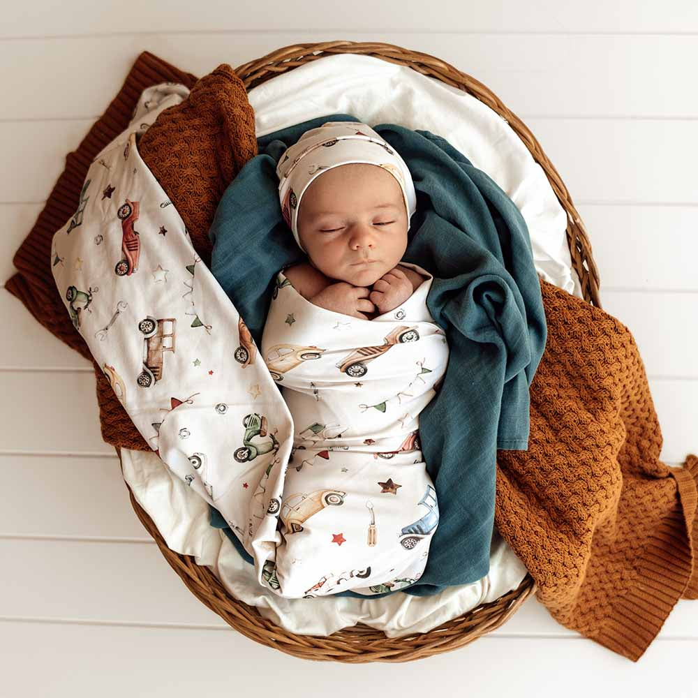 Newborn baby swaddled in a basket with colorful blankets