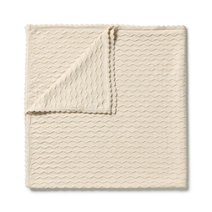 A folded cream-colored textured cloth with a wavy pattern and scalloped edges, displayed on a clean white background.