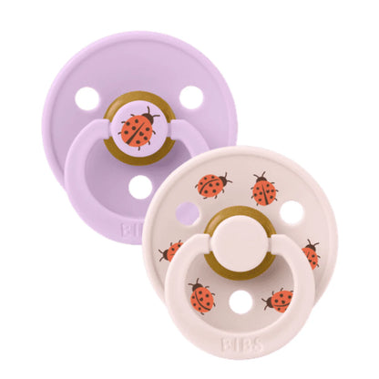 Two baby pacifiers with ladybug design on a white background