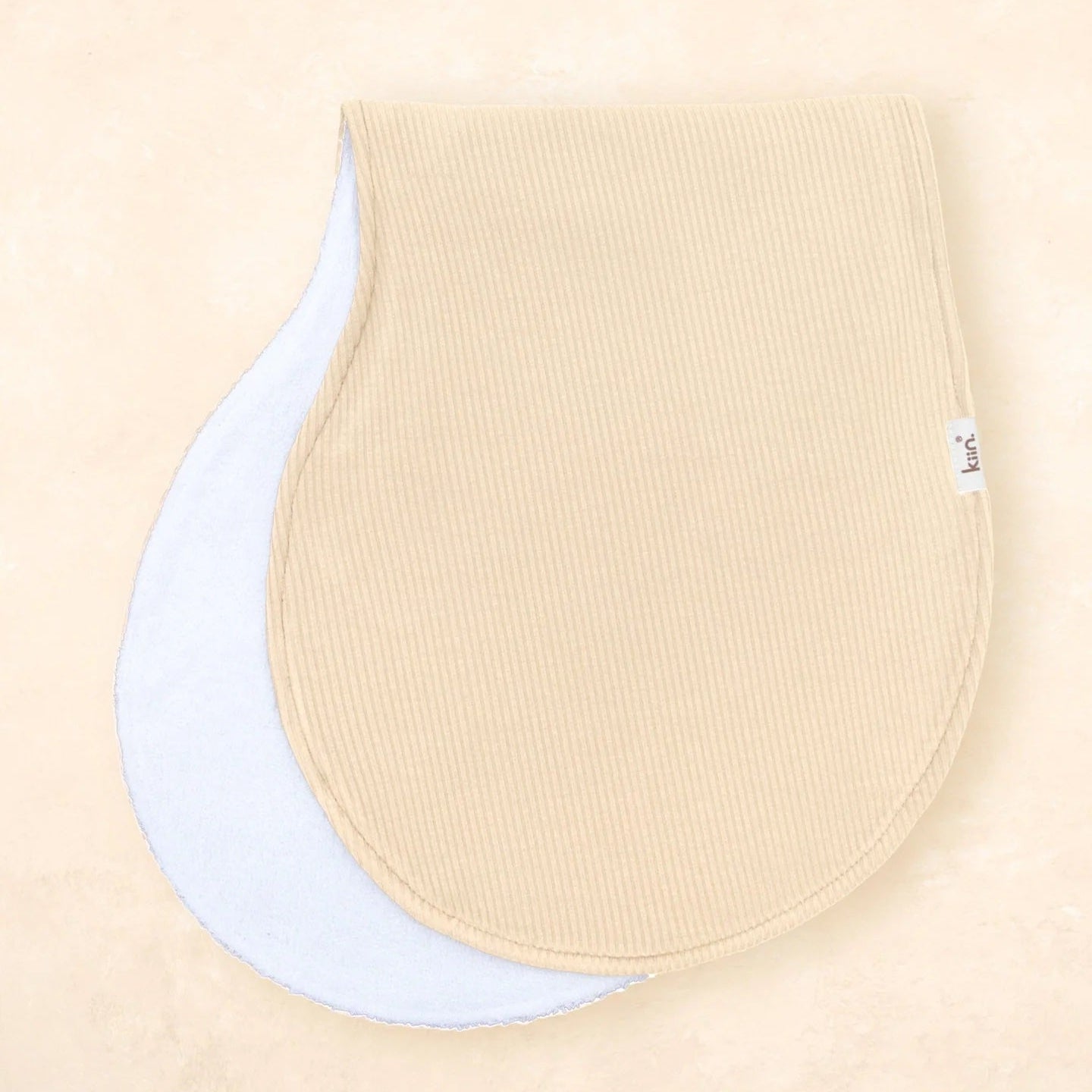 Two beige baby bibs on a beige background