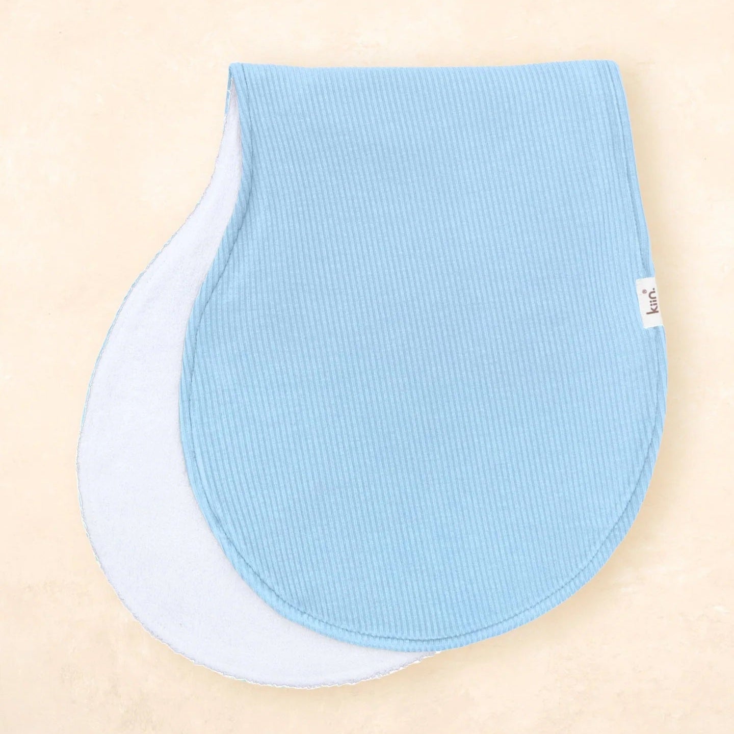 Two blue baby bibs on a beige background