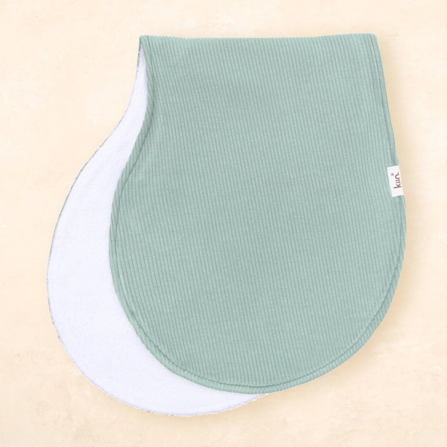Two green baby bibs on a beige background