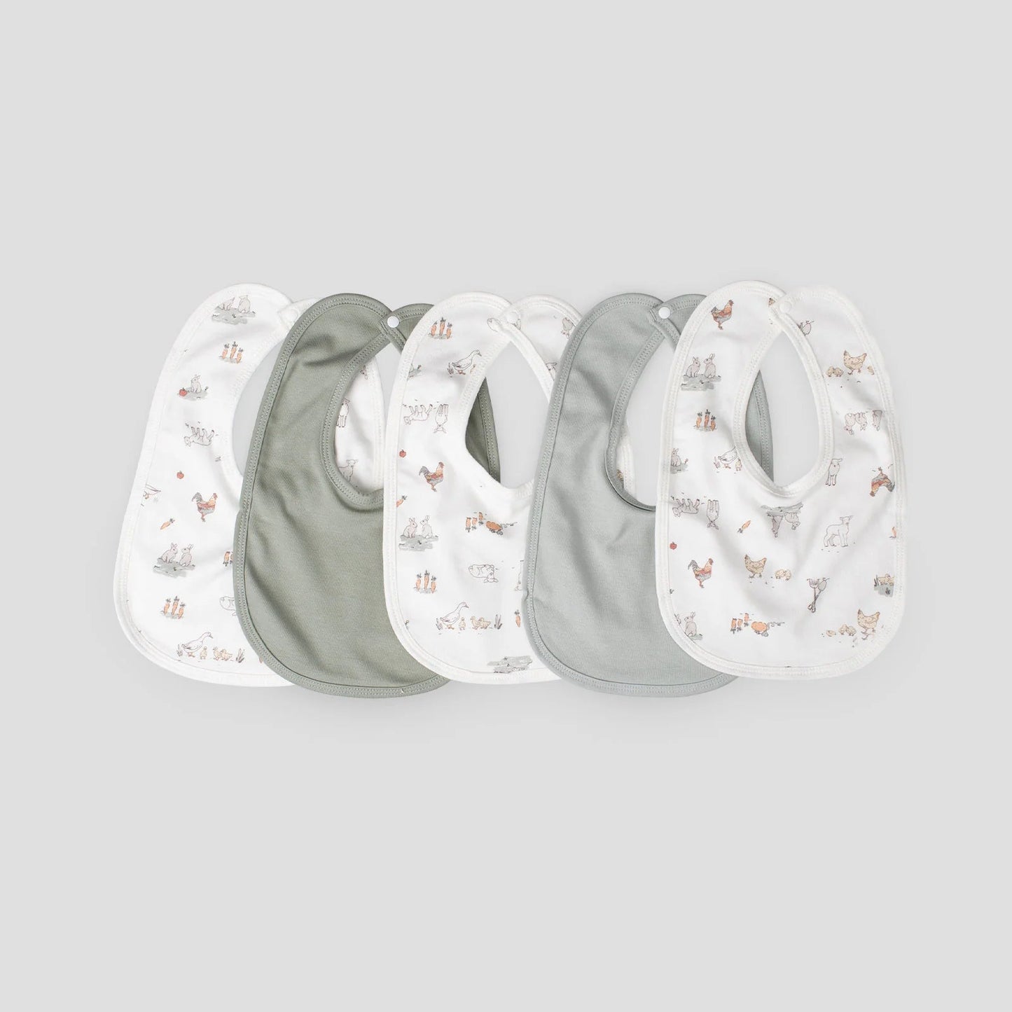 Set of four baby bibs with nature-themed prints on a light gray background