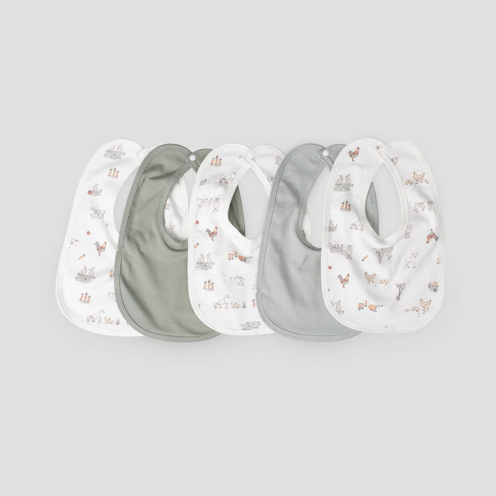 Set of four baby bibs with nature-themed prints on a light gray background