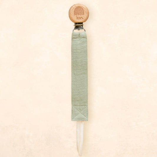 A single product shown against a plain textured beige background. The product is a long, narrow tool with a round light wood top, a pale sage green wrapped handle, and a clear pointed tip extending from the bottom.