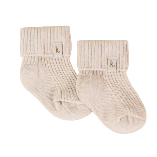 Pair of beige ribbed socks with a brand logo on a beige background