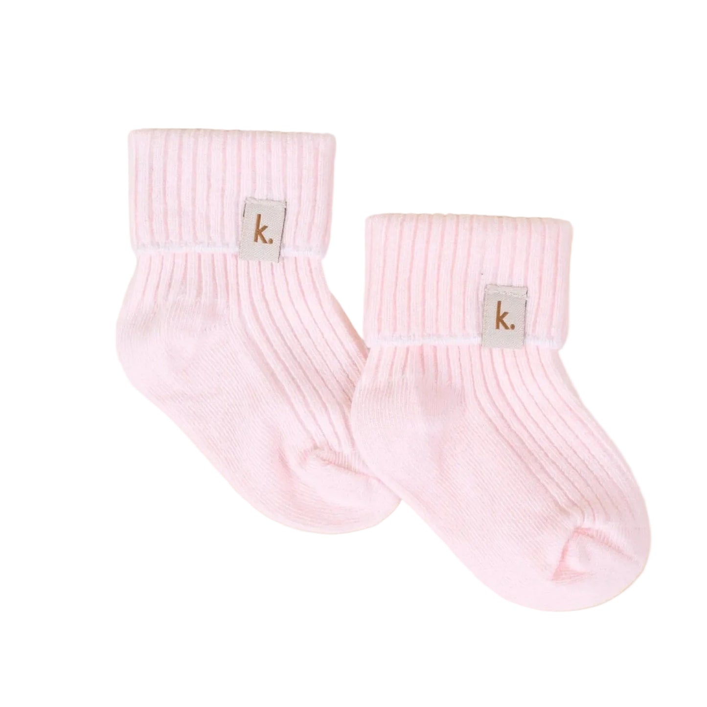 A pair of light pink ribbed ankle socks with a small square gray brand patch featuring the letter 'k' on the cuff, displayed on a textured beige background.