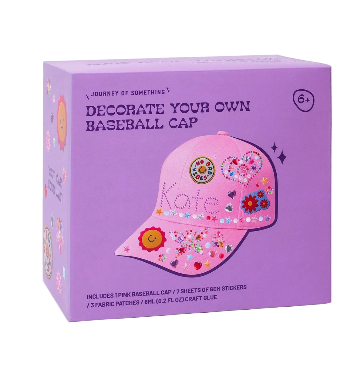 A purple product box for a DIY baseball cap kit, featuring an illustration of a pink cap decorated with flowers, hearts, and the name 'Kate'. The box includes text that says 'Decorate Your Own Baseball Cap' and a small '6+' age rating symbol.