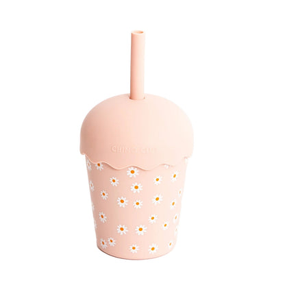 Pink tumbler with floral pattern and straw on a white background