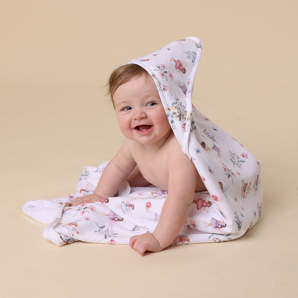 Baby wrapped in a floral towel on a beige background