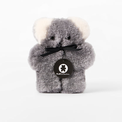 Gray plush bear with a black bow and visible brand logo on a white background