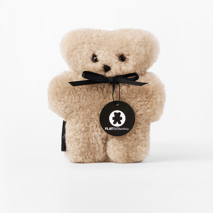 Beige teddy bear with a black bow and 'FLATOUT Stuffed' tag on a white background