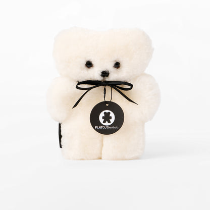 White teddy bear with a black ribbon and tag on a white background