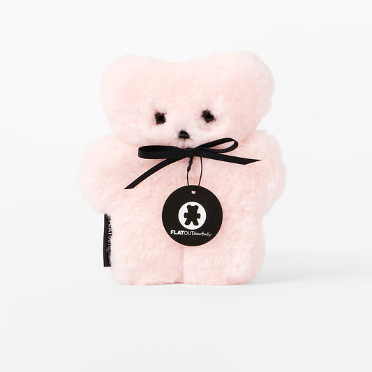 Pink teddy bear with a black ribbon and tag on a white background