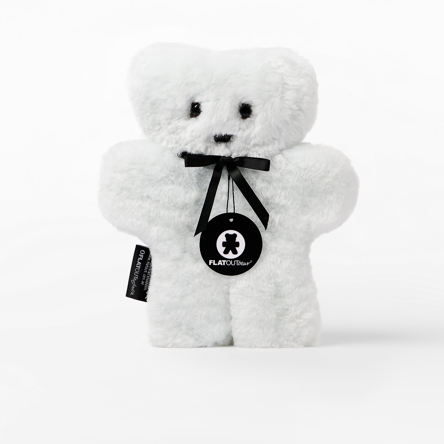 White teddy bear with a black ribbon and tag on a white background