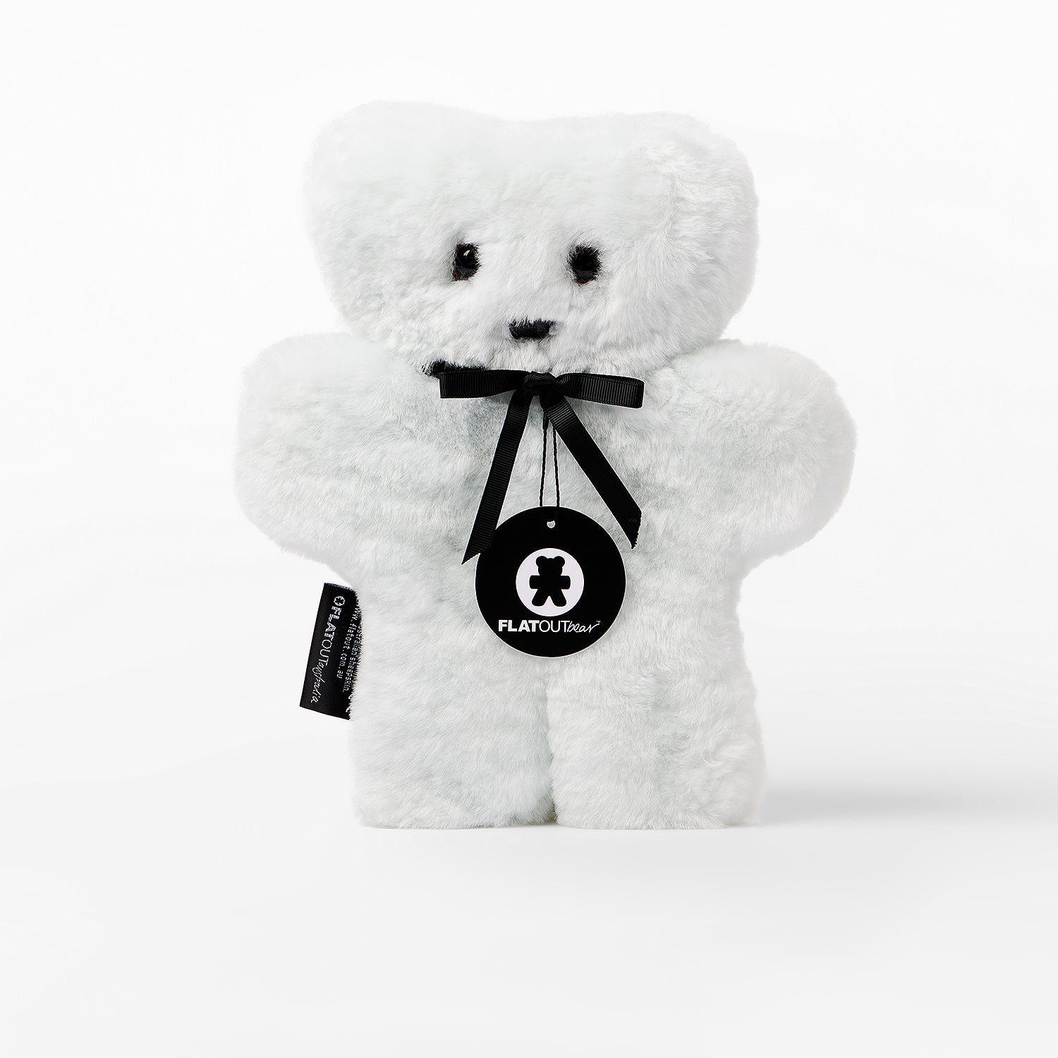 White teddy bear with a black ribbon and tag on a white background