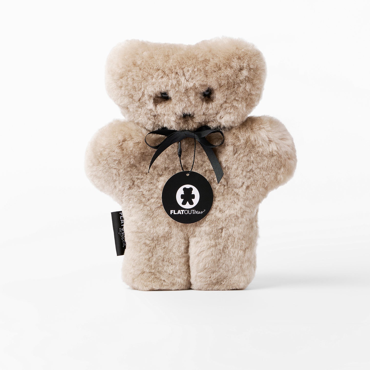 Beige teddy bear with a black tag on a white background