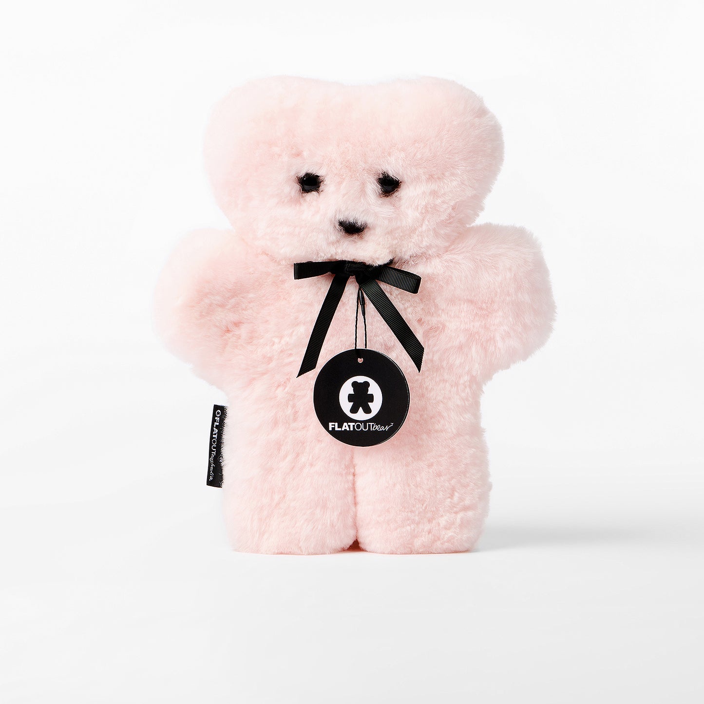 Pink teddy bear with a black ribbon and tag on a white background