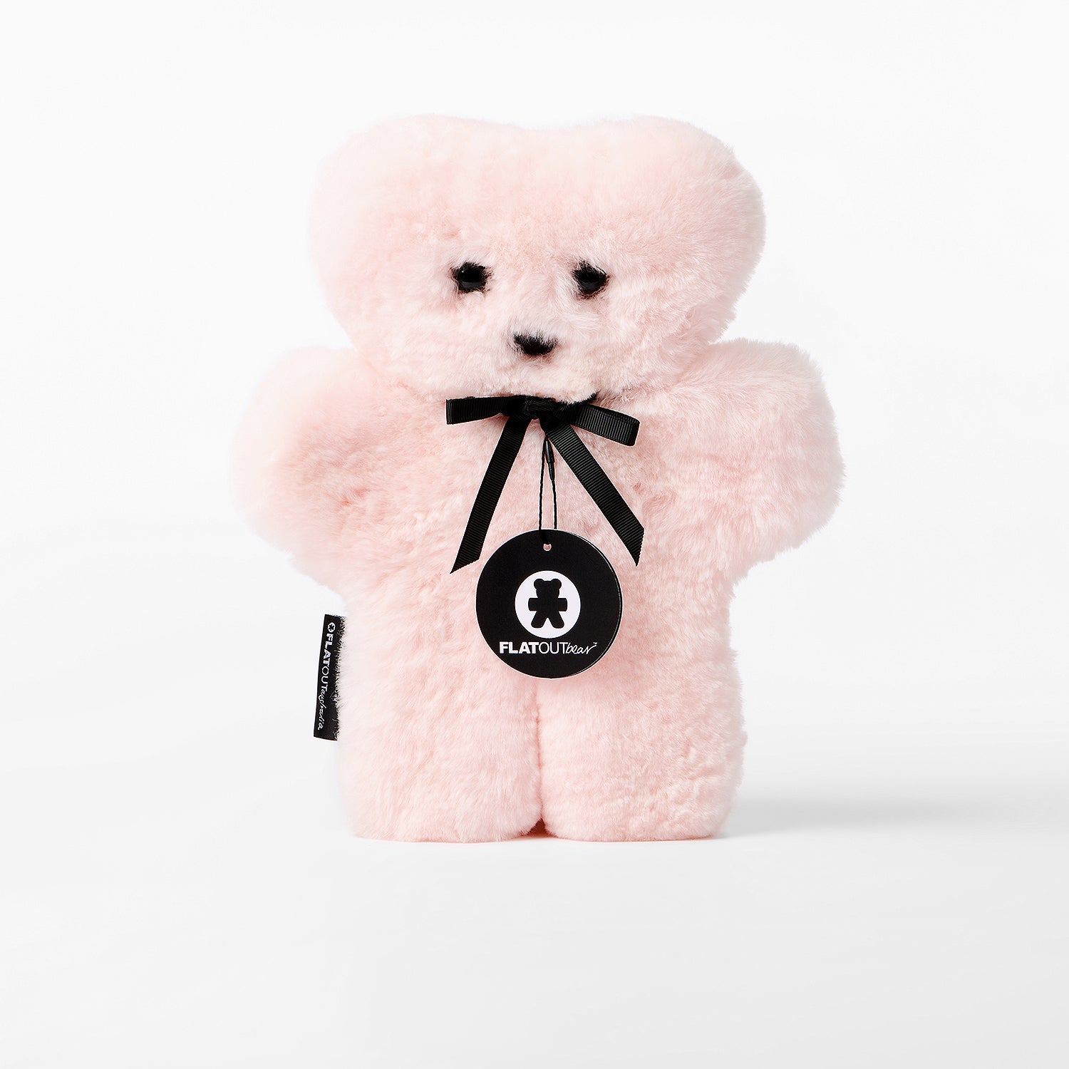 Pink teddy bear with a black ribbon and tag on a white background