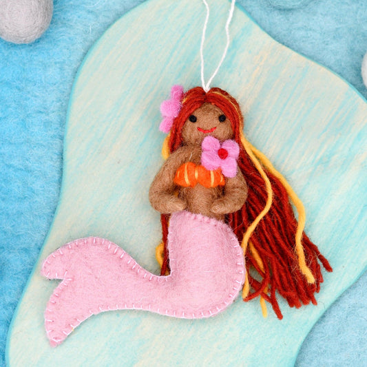 Mermaid toy with red hair and pink tail on a blue and white background