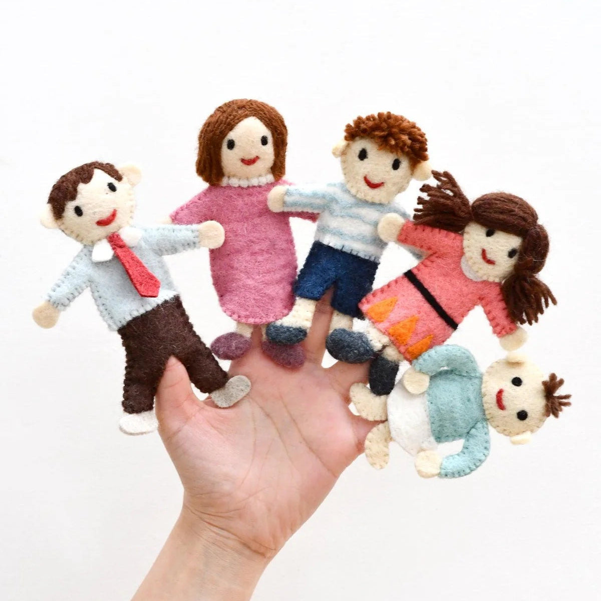 Hand holding finger puppets of a family and pet on a white background