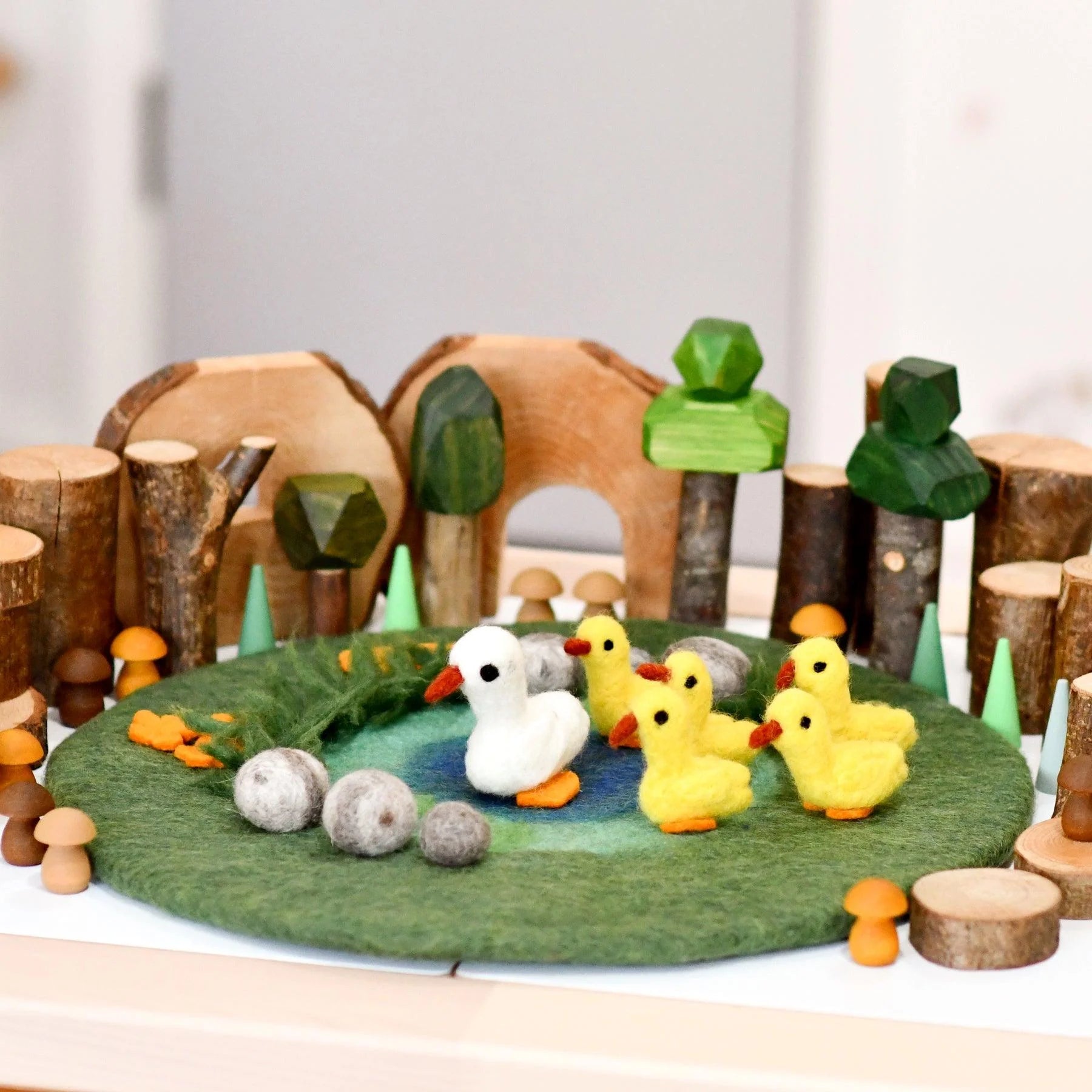 Wooden toy set with ducks and a duckhouse on a felt pond