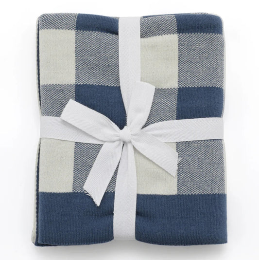 A folded plaid blanket in navy blue and light beige, wrapped with a white ribbon and bow, on a plain white background.