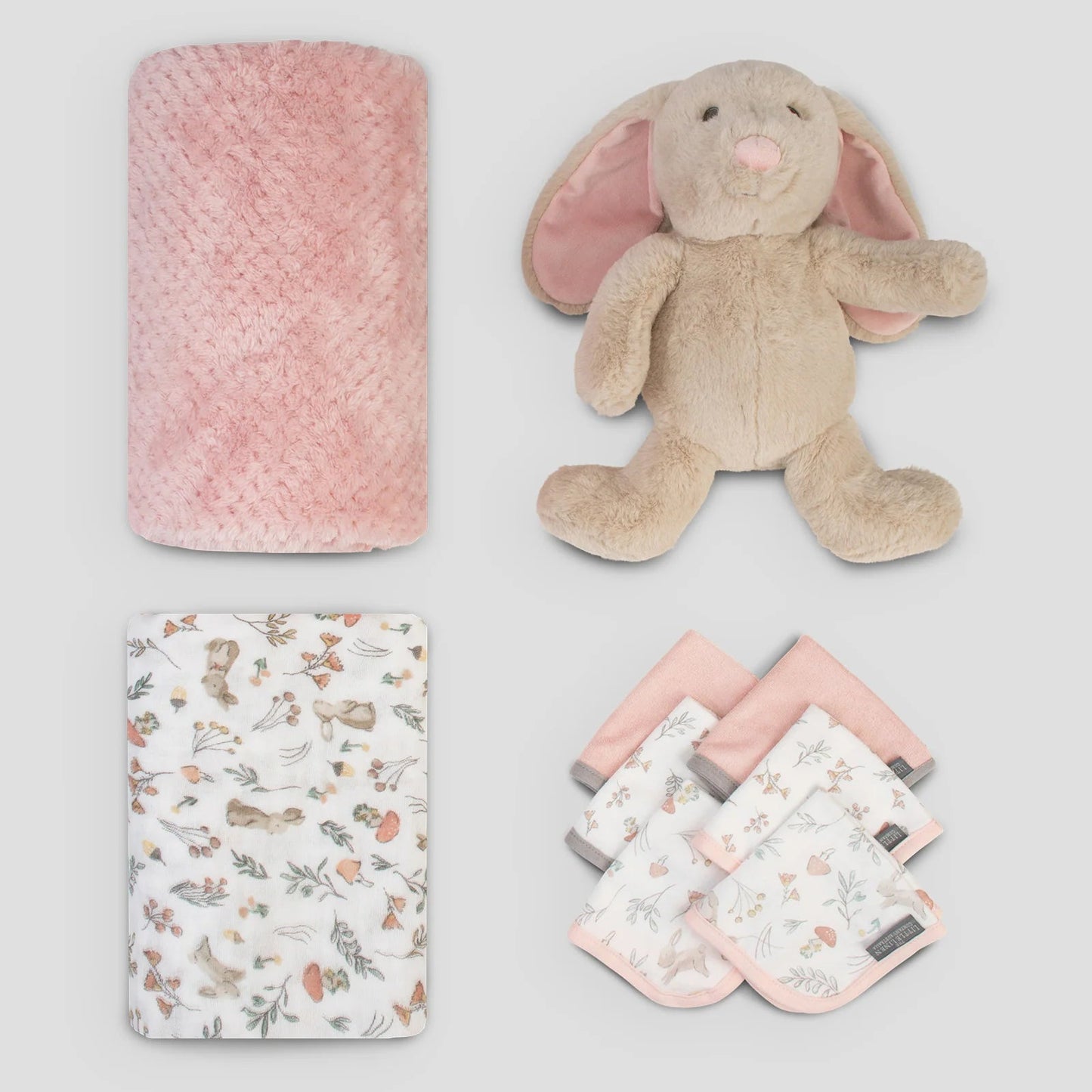 Collection of baby items including a pink plush toy, blanket, and small books on a light gray background