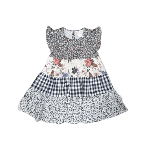 A tiered baby girl's dress with a smocked floral bodice, a central floral panel, a navy and white gingham section, and a navy and white ditsy print skirt, shown flat on a light gray background.