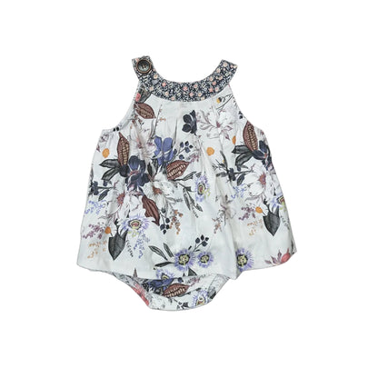 A sleeveless baby romper with a white base and a colorful butterfly and floral print, featuring a patterned floral collar and ruffled shoulder straps, laid flat on a light gray background.