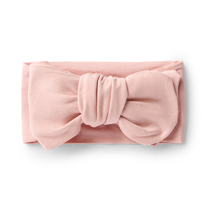 Pink headband with a large bow on a white background