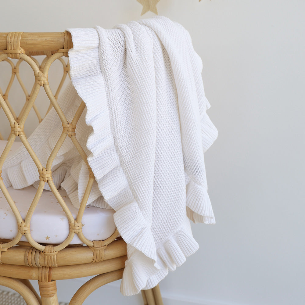 White textured blanket draped over a wicker chair against a light background